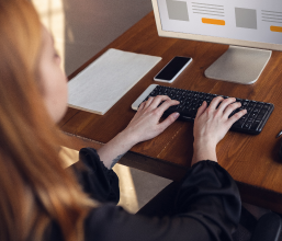 A female professional is working at a desk in Dubai. She is typing on her computer and appears to be focused on her work. This image represents the many opportunities for women to find good jobs in Dubai.