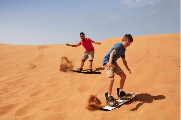 Image of two young boys dune surfing in Dubai