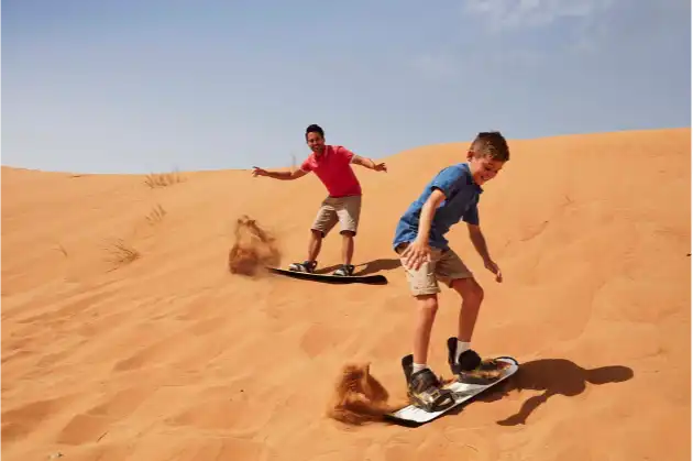 two young boys dune surfing in Dubai